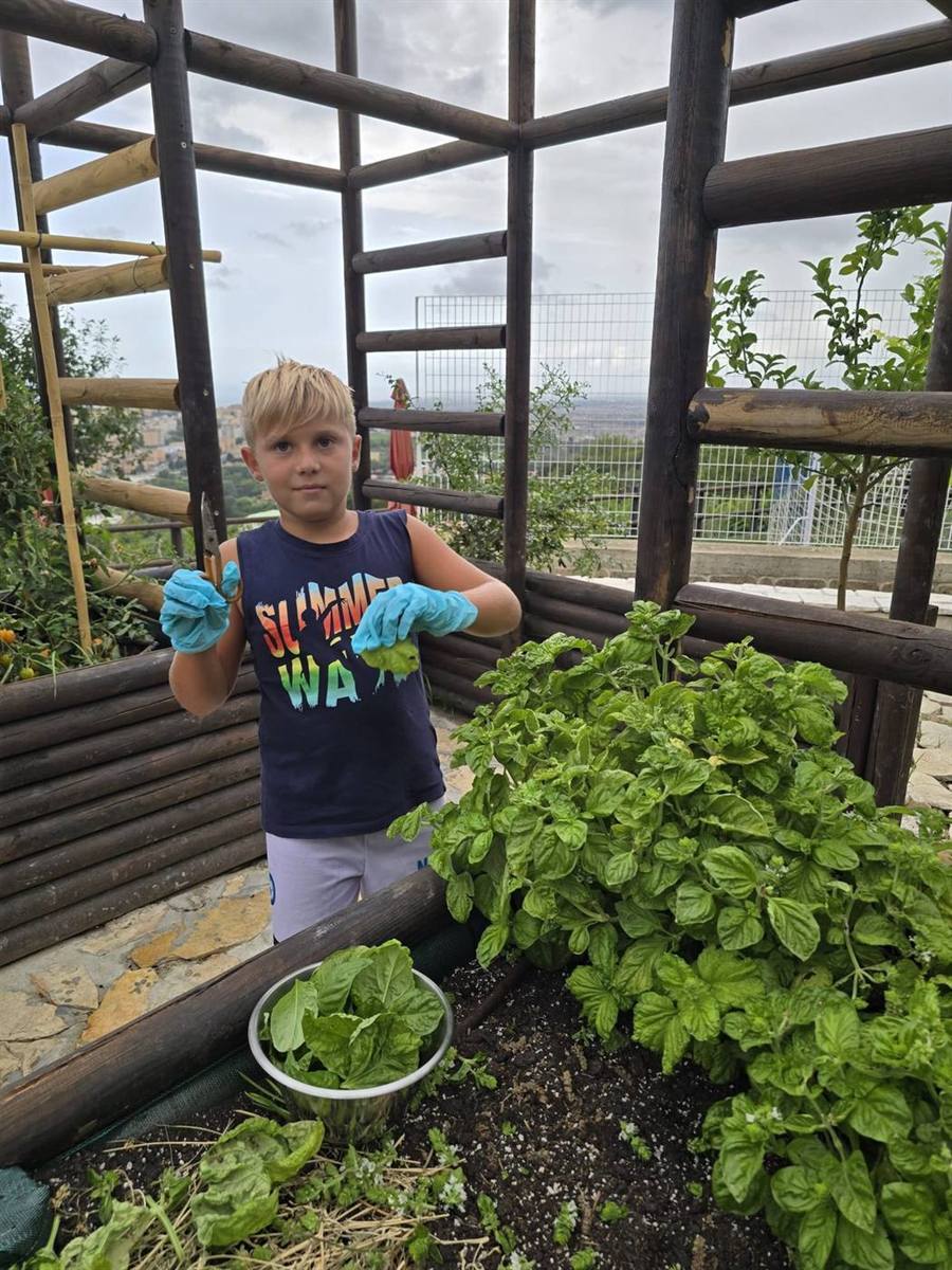 Bambino che semina e coltiva nell'orto rialzato del laboratorio didattico